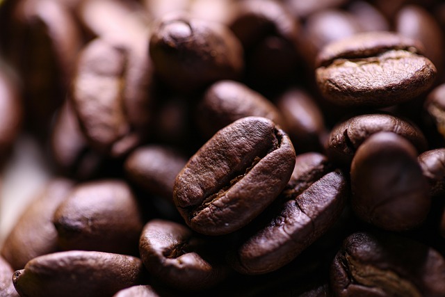Medium roasted Colombian Huila coffee beans with warm caramel colour showing natural oils on a dark wooden surface with burlap sack in background